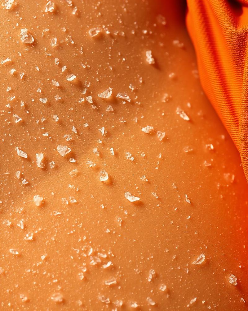 Sea salt on sun-warmed skin next to terracotta swimwear fabric